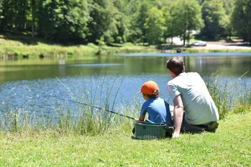 Fotobehang Dad with little boy fishing by mountain lake © goodluz