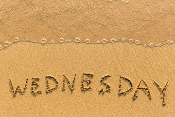 Wednesday - hand-written on the sand in line of the sea surf.
