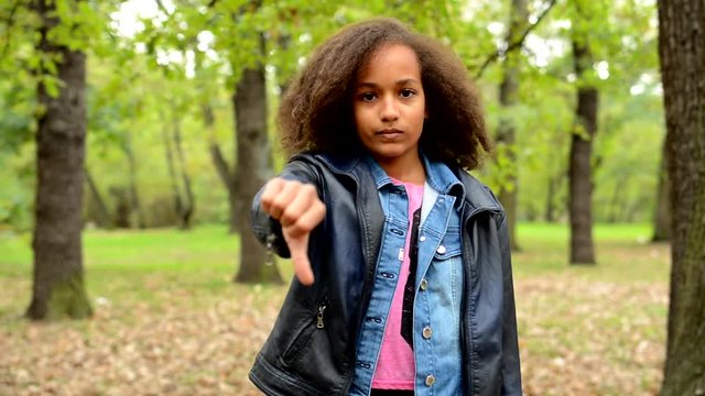 young african sincere girl shows thumb down as disagree - eye contact - say no