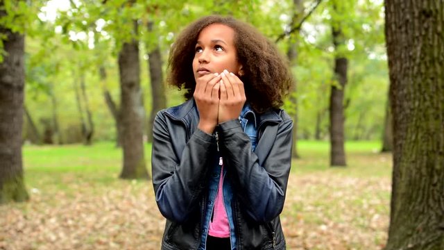 young african frightened girl is appear in unknown place in the park - she is aback and observe the surroundings