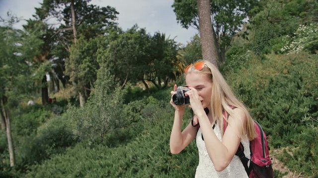 Young woman with retro camera take photos in park