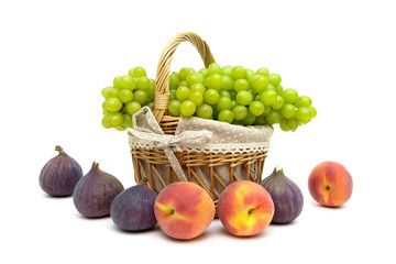 green grapes in a basket, peaches and figs on a white background
