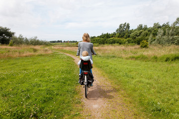 grandmother cycling away in nature with grandchild