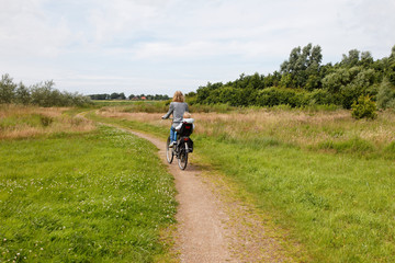 Fototapeta premium woman with child cycling away in nature on bike path