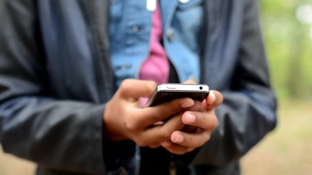 young african girl works with smartphone in the forest - detail of hands