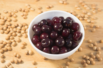 Berries of ripe cherry on a white plate on a background of wooden boards and cherry seed