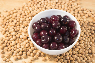 Berries of ripe cherry on a white plate on a background of wooden boards and cherry seed