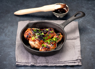 Fried chicken legs with teriyaki sauce in a frying pan