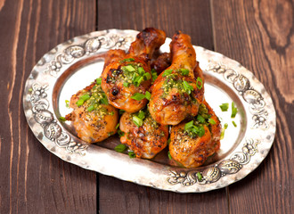 Grilled chicken drumsticks on vintage silver plate.