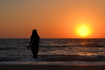 Fototapeta premium Silhouette of a girl in the water at sunrise
