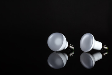 Energy saving lamp on black background. Sales of light bulbs. Advertising for energy-saving bulbs. Place for your text.