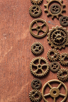 steampunk mechanical cogs gears wheels on wooden background © Olga Miltsova