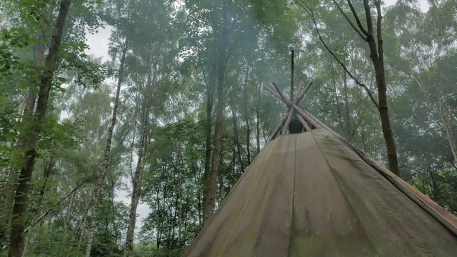 Smoke bellowing from a tipi in the forest