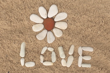 Fototapeta na wymiar flower stone, lying on the sand. made of white pebbles and red. for designers and print