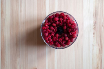 Fresh juicy raspberry in shaker on wooden table