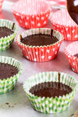 Pouring chocolate cream in the paper muffin wrappers