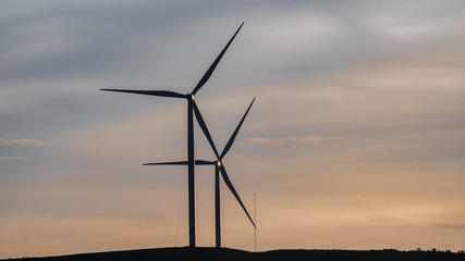 Wind turbine generator silhouette with twilight sky background. 