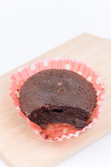 Sliced chocolate muffin on the wooden board in paper wrapper