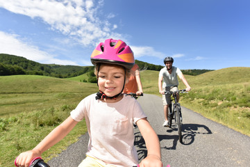 Portrait of little girl riding bike with family