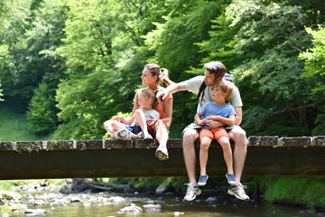 Family sitting on a bridge crossing mountain river