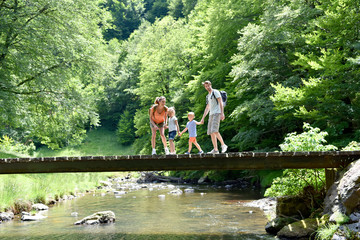 Family of four walking on a bridge crossing the river