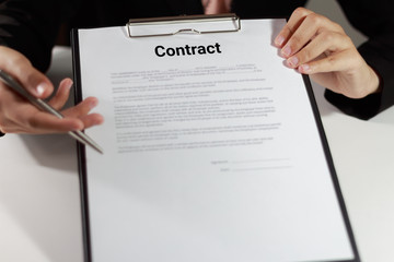 Businesswoman in suit holding and pointing the contract at her