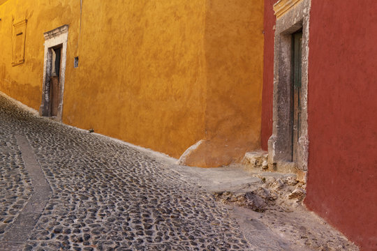 Mexico, San Miguel de Allende. Painted buildings on cobblestone street.