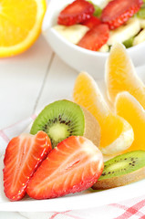 Bowl with fruit salad - pieces of strawberry, oranges, and kiwi