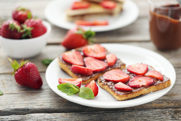 French toasts with chocolate and strawberry on wooden table