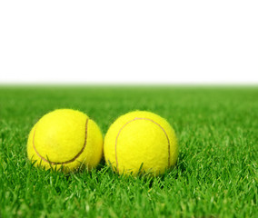Two tennis balls in the green grass.