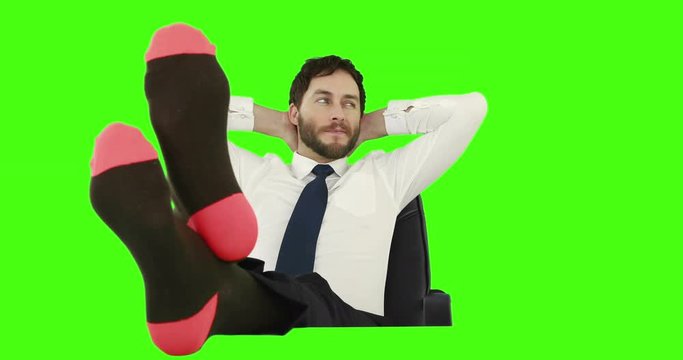 Businessman relaxing in his chair with legs up and with no shoes on green screen