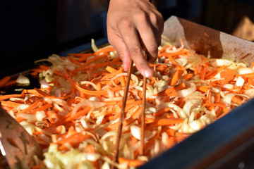 Cook prepares fried vegetables in a wok