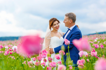 Happy wedding couple in pink poppy field