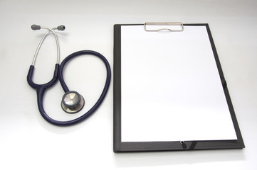 Stethoscope and blank clipboard with a sheet of white paper.