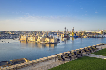 Obraz premium Skyline view of the Grand Harbour and Saluting Battery cannons with Senglea and docks at background, Valletta - Malta