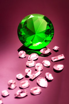 Giant green emerald on a red/ pink background surrounded by precious diamonds leading into the image