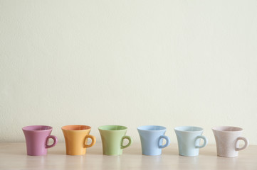 Row of multicolor coffee cups on clear background. Top space of frame.