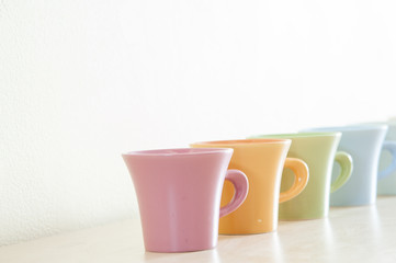 Row of colorful coffee cups on clear background.
