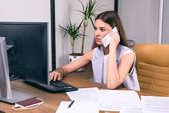Businesswoman using smartphone while working on computer