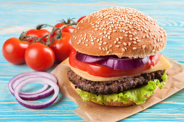 Homemade cheeseburger on blue wooden surface.