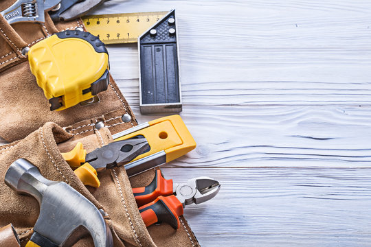 Construction tools in leather building belt on wooden board main