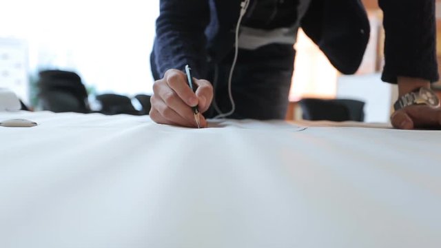 Designer in black jacket masterfully creates draft on sheet of paper