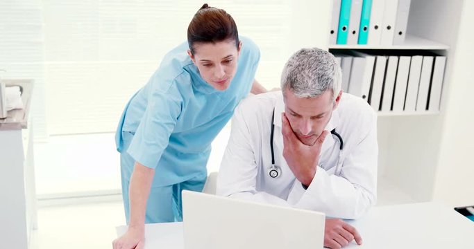 Concentrated doctors looking at laptop in medical office