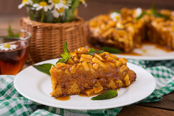 Apple pie with caramel sauce on a wooden background