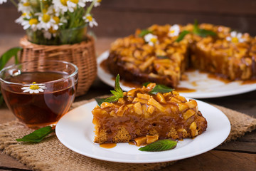 Apple pie with caramel sauce on a wooden background