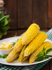 Boiled corn with salt and butter on a white plate