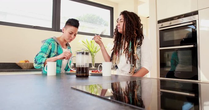 Smiling lesbian couple eating breakfast together in the kitchen at home