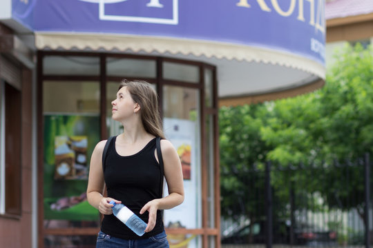 Beautiful girl with bottle of water in his hand looking away