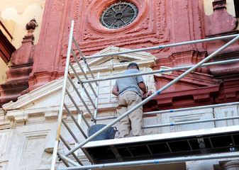 Alba&ntilde;il limpiando la fachada de piedra de una iglesia