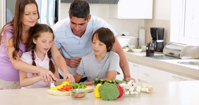 Mother showing her children how to slice vegetables